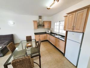 a kitchen with a glass table with chairs and a refrigerator at Apartamentos Graciosamar in Caleta de Sebo