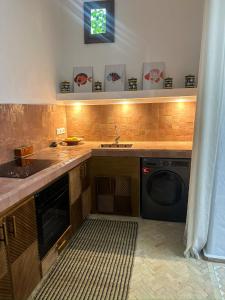 a kitchen with a sink and a washing machine at Riad Olivia in Asilah