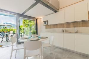 a kitchen with white cabinets and a table and chairs at La Casetta di Lillie in Lierna +16 photos