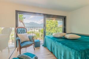 a bedroom with a bed and a chair and a balcony at La Casetta di Lillie in Lierna