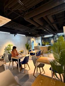 a woman sitting at a table in a room with tables and chairs at Connected Hotel Guro in Seoul