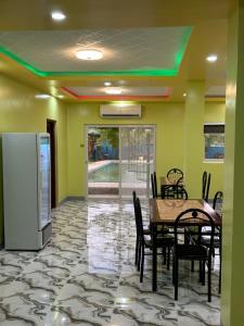 a dining room with a table and chairs and a refrigerator at Scarlett Near Mount Zion Laguit Padilla in Bugallon