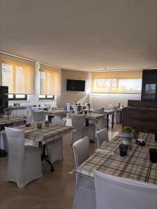 a dining room with tables and white chairs at Hotel Brixellum in Brescello