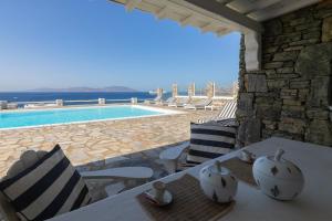 a patio with a table and chairs and a swimming pool at MichaelAngelo Villa in Mikonos