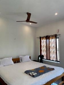 a bedroom with a bed with a ceiling fan at Mango tree room stay in Gokarna