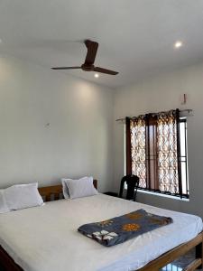 a bedroom with a bed with a ceiling fan and a window at Mango tree room stay in Gokarna