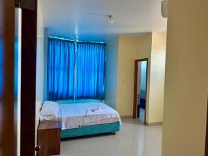 a bedroom with a bed with blue walls and a window at Hospedaje El Imperio in Tarapoto +3 photos