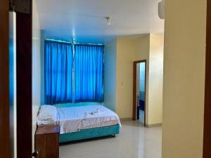 a bedroom with a bed and a window with blue curtains at Hospedaje El Imperio in Tarapoto