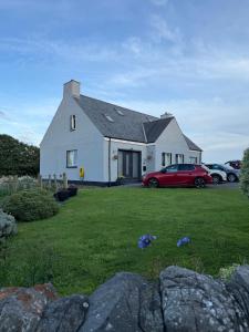 a white house with a red car in a yard at Islecroft House Bed & Breakfast in Isle of Whithorn
