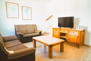 a living room with a tv and a chair and a table at Apartamentos Graciosamar in Caleta de Sebo