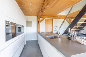 a kitchen with white cabinets and a wooden ceiling at Buytenplaats Villa 189 in De Koog +24 photos