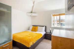 a small bedroom with a bed with a yellow blanket at Newcastle City Centre Apartment in Newcastle upon Tyne
