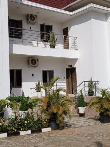 a white building with potted plants in front of it at Stallion Luxury Suites in Ado