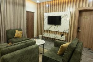 a living room with two chairs and a television at Stallion Luxury Suites in Ado