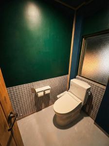 a bathroom with a toilet and a green wall at 山過HOTELs in Chino