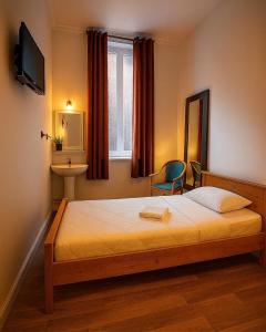 a bedroom with a bed and a chair and a window at Hôtel Le Paris Brest in Lens