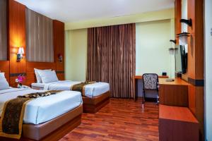 a hotel room with two beds and a desk at Tripletree Stefani Hotel in Pekanbaru +59 photos