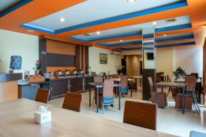 a dining room with tables and chairs and a kitchen at Tripletree Stefani Hotel in Pekanbaru