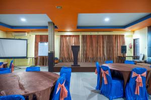 a conference room with a table and chairs and a screen at Tripletree Stefani Hotel in Pekanbaru