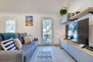 a living room with a couch and a flat screen tv at Valletta Marina View - Seafront Apartment in Tal-Pietà