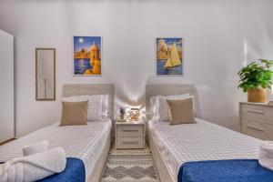 a bedroom with two beds and a potted plant at Valletta Marina View - Seafront Apartment in Tal-Pietà