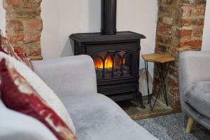 a fireplace in a living room with two chairs at Host & Stay - Thimble Cottage in Whitby