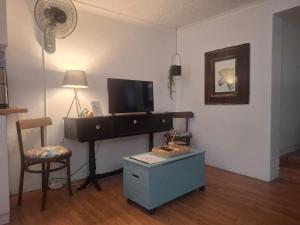 a living room with a tv and a desk and a chair at Melrose Garden Cottages - Hibiscus Cottage in Durban
