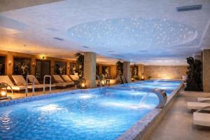 a large pool in a hotel with chairs and a swimming pool at Prezident Palace Belgrade - Rooftop Pool & Spa Hotel in Belgrade