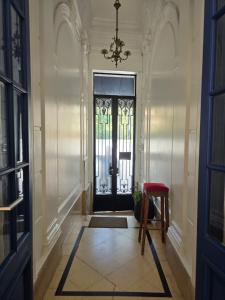 a hallway with a door with a red chair and a chandelier at Meridiano Hostel Boutique in Buenos Aires