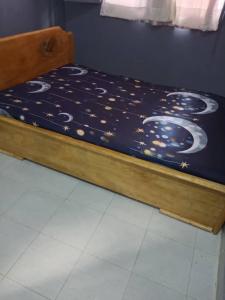 ein Bett mit einer blauen Bettdecke mit Mond- und Sternenmotiv in der Unterkunft HÔTEL AMANI - Kikwit in Kizamba