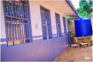 ein Gebäude mit blauen Türen und einem blauen Fass in der Unterkunft HÔTEL AMANI - Kikwit in Kizamba