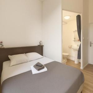 a bedroom with a bed with a book on it at Hôtel Le Paris Brest in Lens
