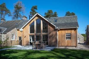 a barn style house with a patio and a large window at Kennels Cottage in Buchanty