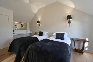 two beds in a room with white walls at Kennels Cottage in Buchanty