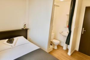 a small bathroom with a bed and a toilet at Hôtel Le Paris Brest in Lens