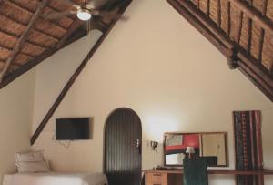 an attic bedroom with a bed and a tv at Blue Hills Lodge in Midrand