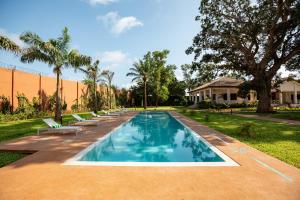 a swimming pool with lounge chairs in a yard at Native Hotels Ouidah in Kika