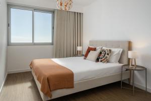 a white bedroom with a large bed and two windows at BAsia Apartment by An Island Apart in Funchal