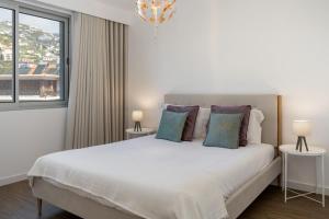 a bedroom with a large white bed with two lamps at BAsia Apartment by An Island Apart in Funchal