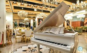 a white piano sitting in a room with a restaurant at Prezident Palace Belgrade - Rooftop Pool & Spa Hotel in Belgrade