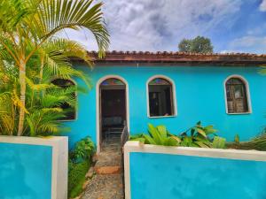 a blue house with a palm tree in front of it at Suítes Aconchego - Pousada Rústica & Café da Manhã Especial in Lençóis