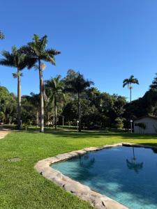 a swimming pool in a park with palm trees at Pousada Villa da Serra in Brumadinho