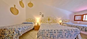 a bedroom with two beds and two lights on the wall at Casa Gabriella in Fetovaia