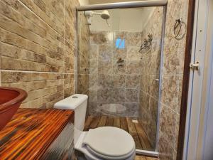 a bathroom with a toilet and a shower at Suítes Aconchego - Pousada Rústica & Café da Manhã Especial in Lençóis +8 photos