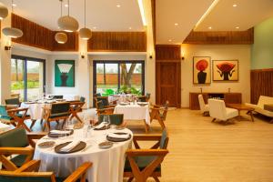 a restaurant with white tables and chairs and windows at Native Hotels Ouidah in Kika