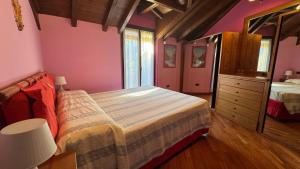 a bedroom with pink walls and a bed and a dresser at Casa Zia Pia in Baveno
