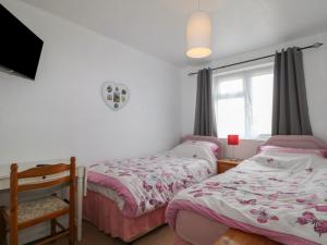 a bedroom with two beds and a window at 90 Bay View in New Romney