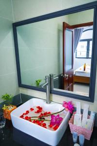 a bathroom with a sink with a mirror and flowers at Côn Sơn Victory Hotel in Con Dao +76 photos