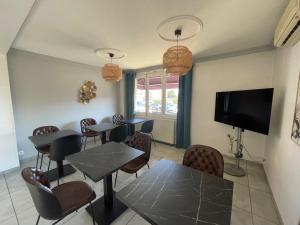 a dining room with tables and chairs and a flat screen tv at "Contact Hôtel" Le Saint Rémy - Chalon Sud in Saint-Rémy