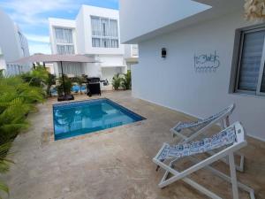 a villa with a swimming pool and two lounge chairs at Damani Modern Pool Villa Escape in Punta Cana